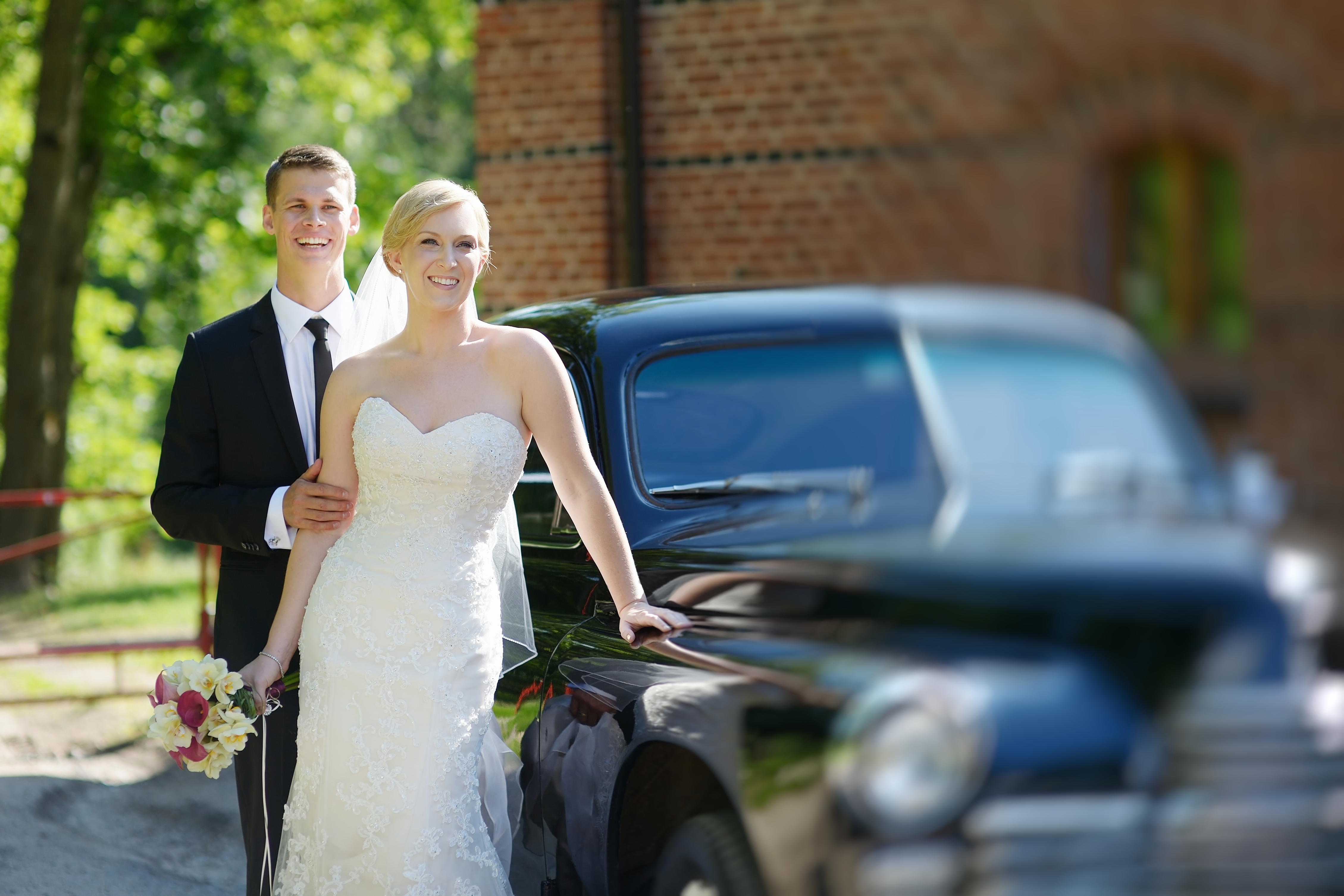 Bride and groom beside a vintage car on their wedding day